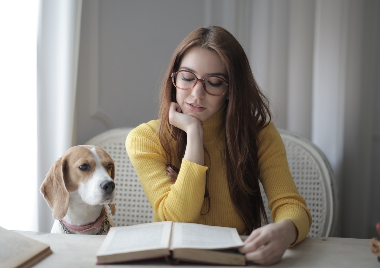 Kobieta czyta dokumenty - rodowód i metrykę psa, obok niej pies.